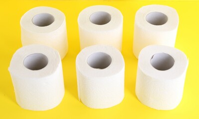 Many soft toilet paper rolls on yellow background, closeup