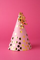 One beautiful party hat with serpentine streamers on pink background