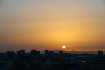 生駒山系から朝日が登る時。神戸市内から芦屋のビルと山並みをシルエットで撮影。