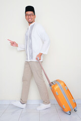 Full body portrait of moslem man walking and pulling suitcase