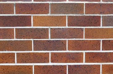 Close up textured background of a red-brown brick wall with white mortar