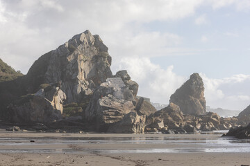 A rocky beach with a large rock formation in the background