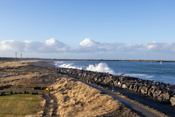 Waves crash along shore wall