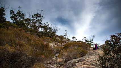 brave fit girl climbing to the top of mount maroon; rock scrambling in mount barney national park near brisbane, queensland, australia