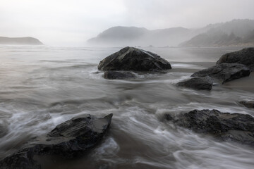 A rocky shoreline with a large rock in the foreground