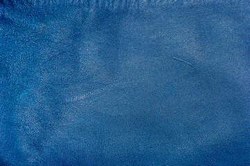 Blue leather background with scratches. Macro photo of genuine leather dyed in blue.