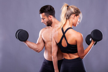 Sports couple with dumbbells on a dark background - 749681224