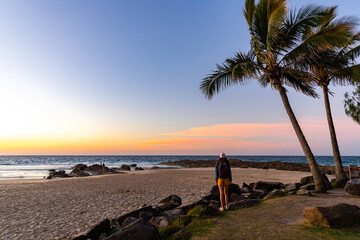 long hair woman enjoying a colorful sunset over the beach in coolangatta near point danger, gold coast, queensland, australia;