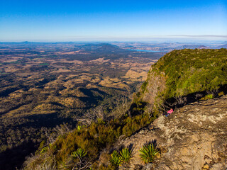 Fototapeta premium aerial view of hiker enjoying a sunset over mountains in main range national park, queensland, australia - famous bare rock lookout