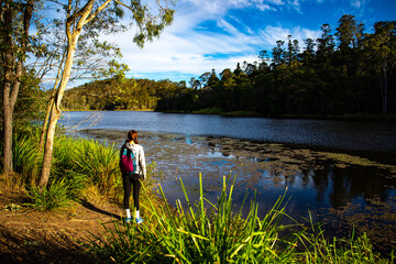 pretty girl with a backpack enjoys afternoon walk at enoggera reservoir in brisbane, queensland,...