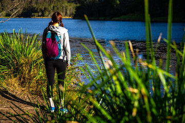 pretty girl with a backpack enjoys afternoon walk at enoggera reservoir in brisbane, queensland, australia; warm sunset in a park