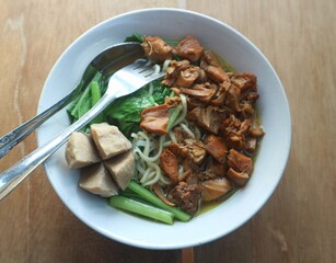 Chicken noodles are eaten using a spoon and fork
