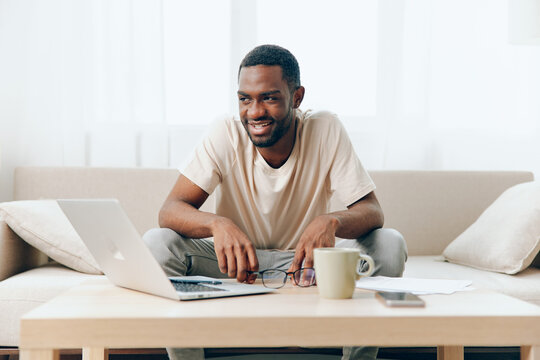 Tired African American Freelancer Typing on Laptop in a Home Office, Experiencing Sadness and Unhappiness This Depicts the Crisis and Stress Faced by Modern Millennial Workers The Man is Sitting on a
