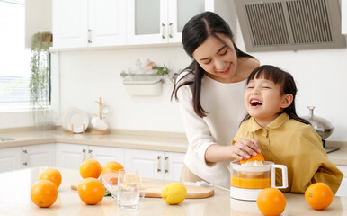 Making in the kitchen Asian mother making juice for daughter to drink