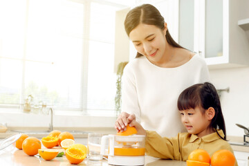 Making in the kitchen Asian mother making juice for daughter to drink