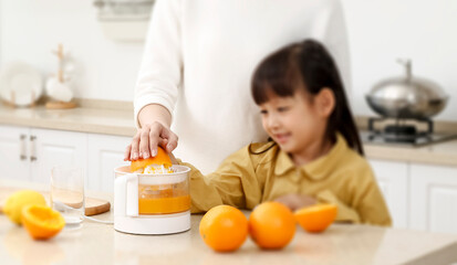 Making in the kitchen Asian mother making juice for daughter to drink