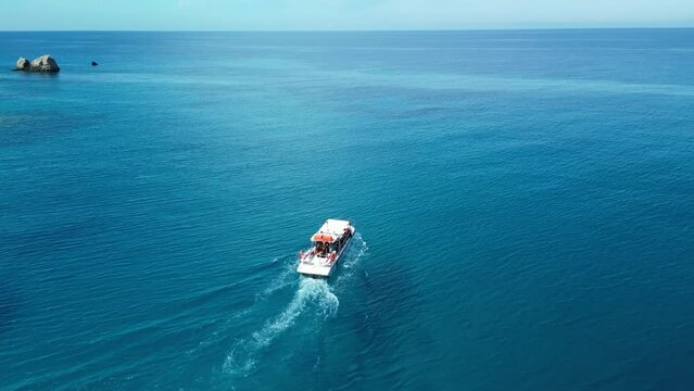 Aerial view of sailing boat with white foamy trail in blue transparent water