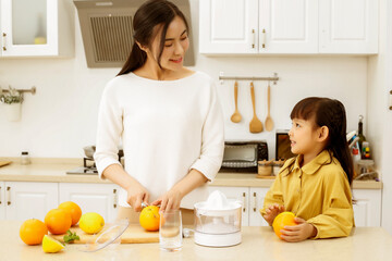 Making juice in the kitchen. Asia. Mother and daughter making juice together.