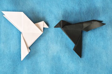 White dove and black rave paper origami in blue background. Good and evil, face fear and opposite...