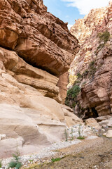Bizarre grandeur of mountains in path of shallow stream in gorge Wadi Al Ghuwayr or An Nakhil and wadi Al Dathneh near Amman in Jordan