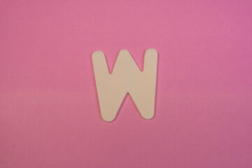 Letter W in wood on a pink background