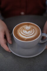 Cup of coffee latte with heart shape in cafe  in coffee shop with hand 