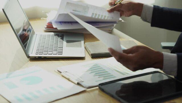 Businessman checks income and expenses from summary graph for accounting accuracy, business auditing concept, 4k close-up video