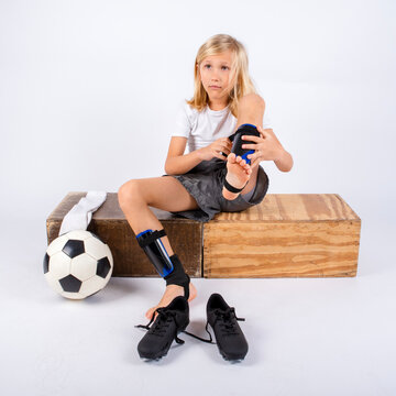 Young soccer player putting on shin guards while dressing for a game