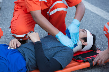 Injured man on patient transport stretcher. Ambulance staff member assisting injured person with transport stretcher. Paramedics assisting injured person first aid on road