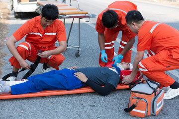 Injured man on patient transport stretcher. Ambulance staff member assisting injured person with...