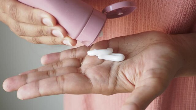 Close up of woman pouring moisturizing cream on hand f