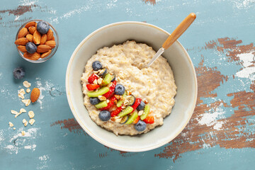 Oatmeal porridge with fruit and berries in bowl on the table. Homemade healthy breakfast cereal...