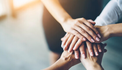 Top view of stacked hands symbolizing unity and teamwork under bright white backlight against a clean background