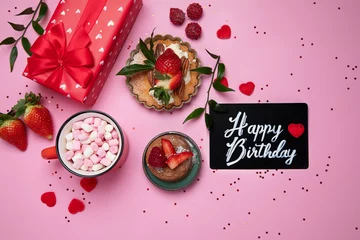 Foto op Plexiglas Festive pink background with cupcake, strawberries, chocolates, hot drink. Birthday celebration © bit24