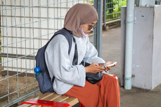 Asian hijab woman using phone to connect with other people for various task such study and business