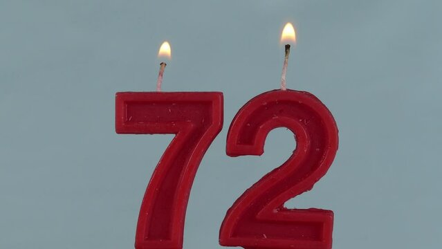close up on red number seventy two birthday candle on a white background.