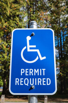 Handicap parking sign with trees in the background. Reserved parking lot for mobility or disable people