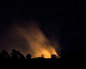 Wildfire in the mountains during starry night 
