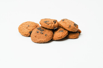 Chocolate chip cookies on white ground together in a small pile.