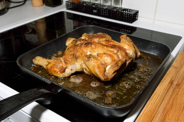 Fried chicken with a golden crust in a frying pan at home