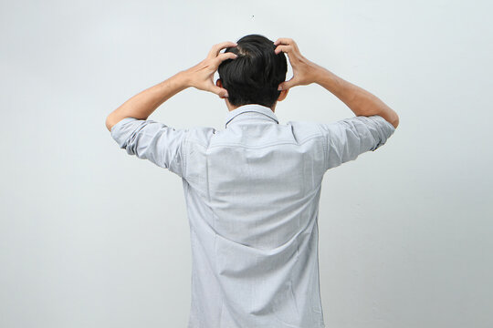 back view of asian indonesian man with hand grab his head showing stressful confused gesture. isolated background