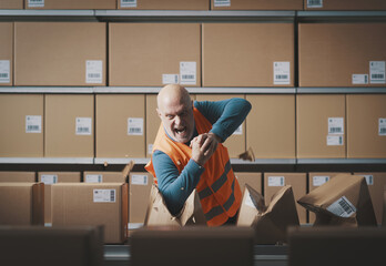 Furious rebellious worker tearing boxes at the warehouse