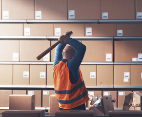 Crazy rebellious worker hitting boxes with a bat