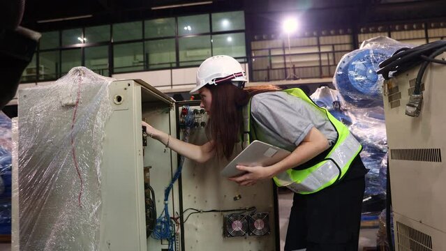 Female engineer carefully check control cabinet inspects electrical system new robot zone in robot warehouse covered with clear dust proof plastic and maintenance service waiting for electrical test.