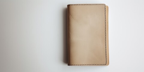 A manuscript is placed on a white background, featuring a beige leather passport folio, light bronze in color, embodying prairiecore and industrial materials.