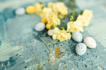 Yellow beautiful flowers and blue and yellow colored easter eggs on a blue picturesque oil painting...
