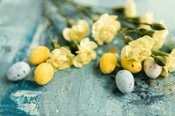 Yellow beautiful flowers and blue and yellow colored easter eggs on a blue picturesque oil painting background close up. Mockups. Layout. Spring pastel background. Easter pastel contemporary backgroun