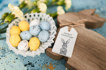 Yellow beautiful flowers and blue, yellow colored easter eggs in wicker basket, and easter bunny on a blue picturesque oil painting background close up. spring Mockups.Layout. Easter pastel background