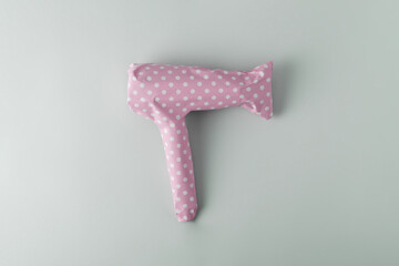 Hair dryer packaged in pink polka dot gift paper on a blue pastel background. Creative gift and...