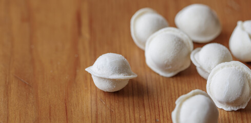 Fototapeta na wymiar Frozen white dumplings on a wooden board, close-up, macro